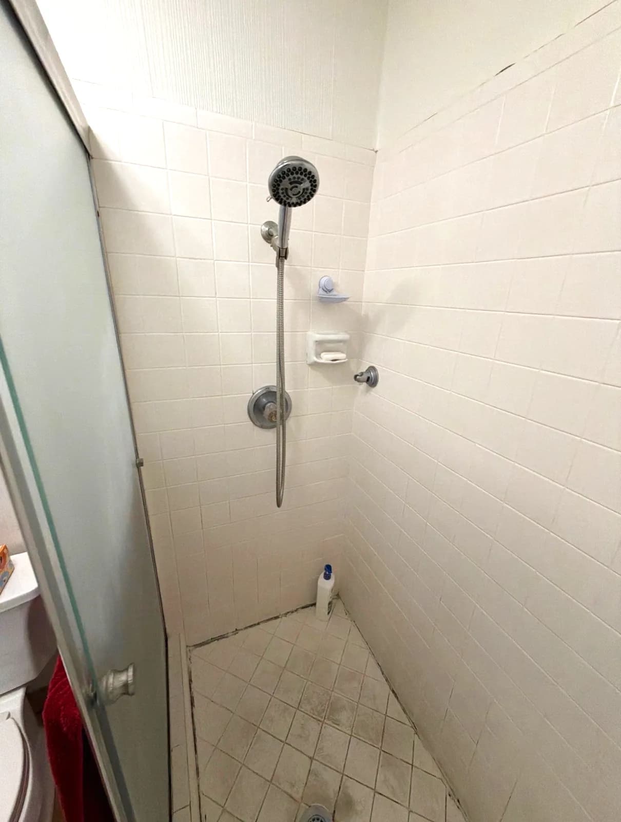 Before: small square white tile and a tiled shower pan with a fixed shower head in a Citrus Heights master bathroom
