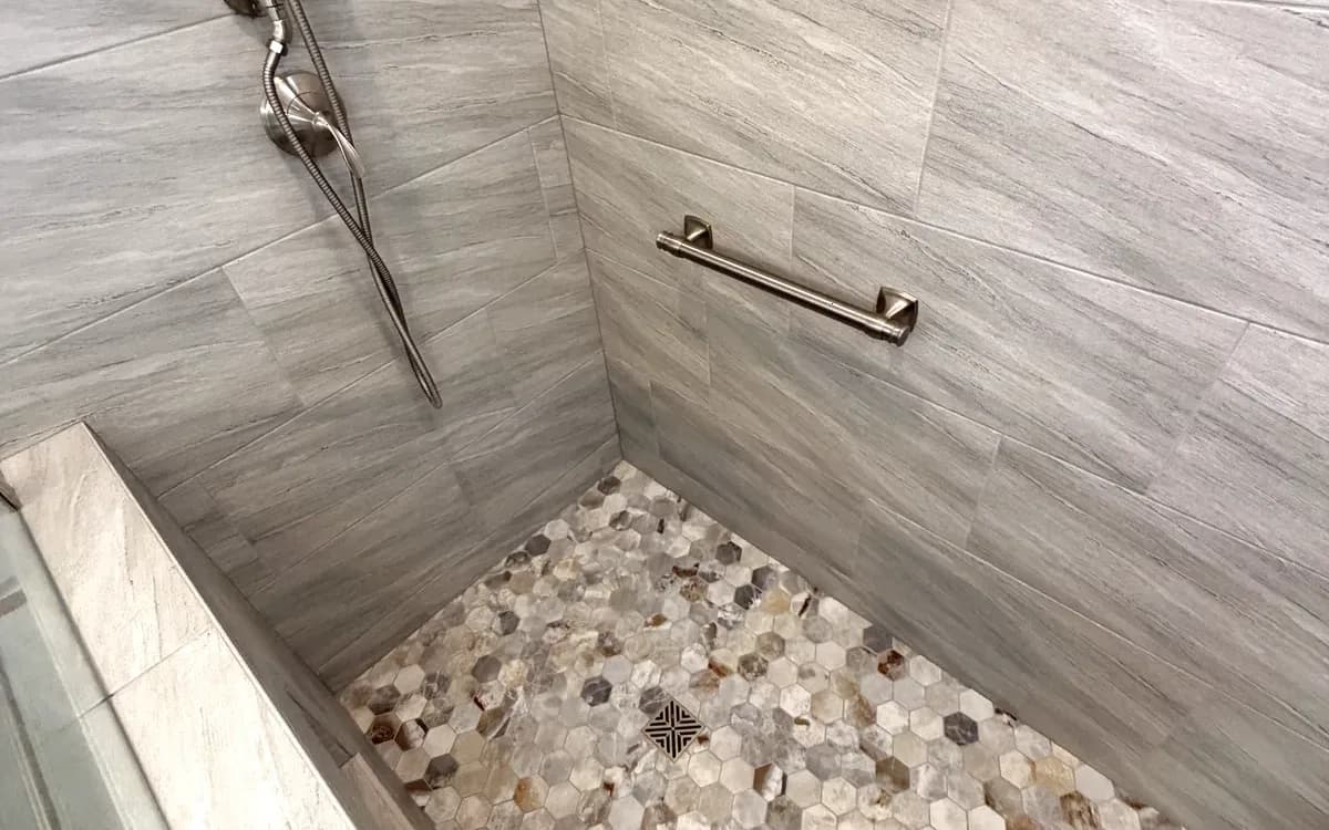 Natural pebble stone accent wall and tiled bench inside the shower