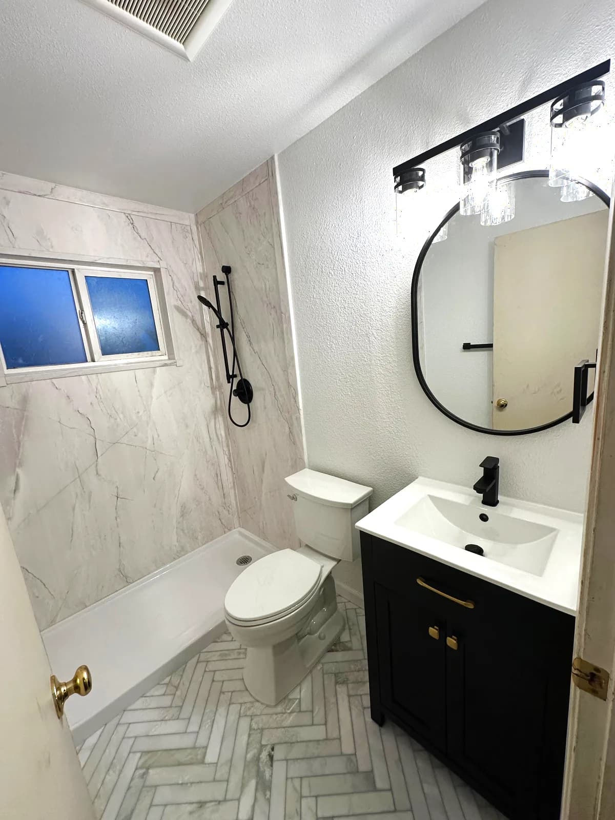 After: low-threshold shower with marble-look acrylic walls and handheld on a black slide bar