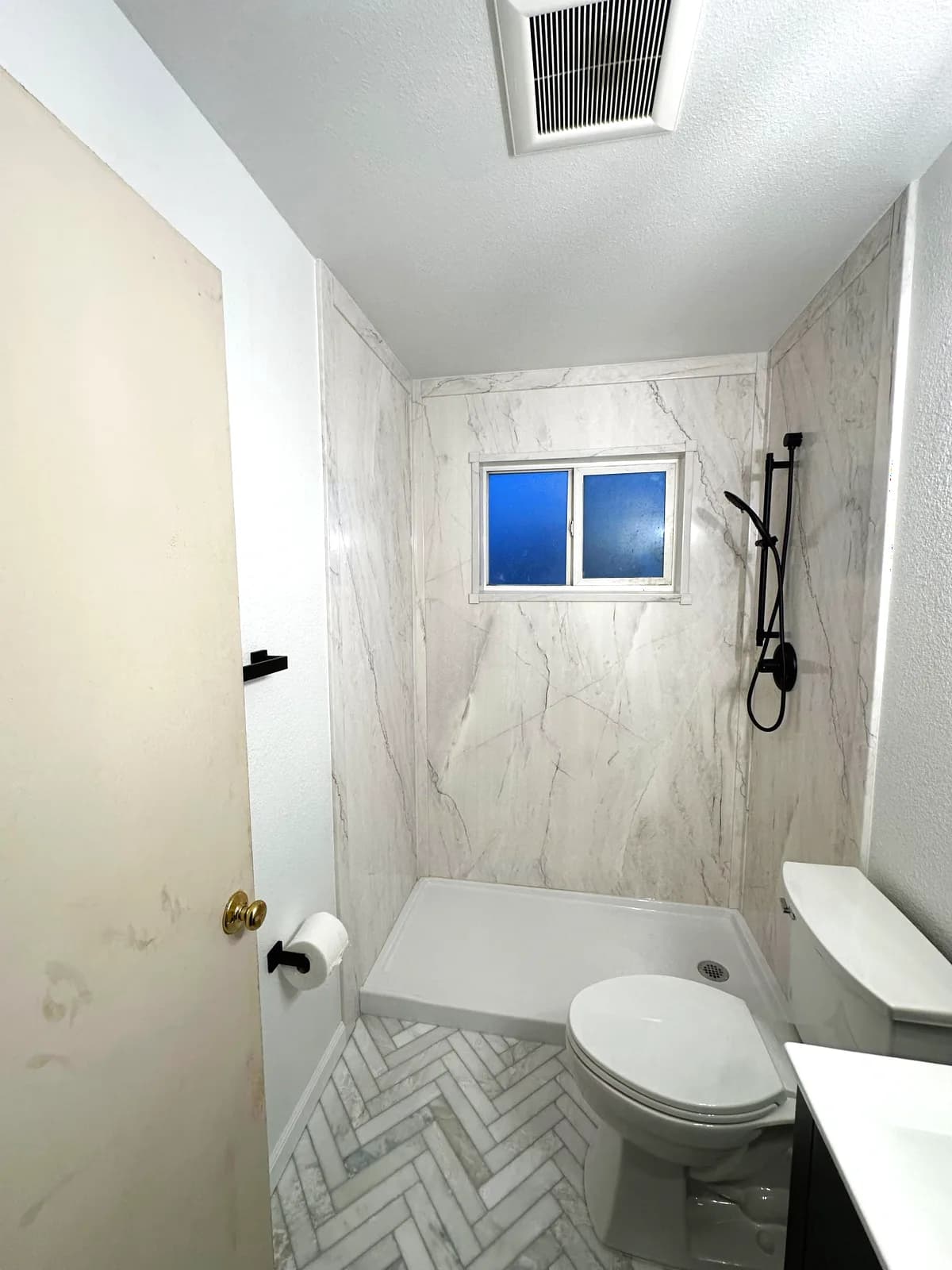 After: marble herringbone floor tile beside the toilet and vanity