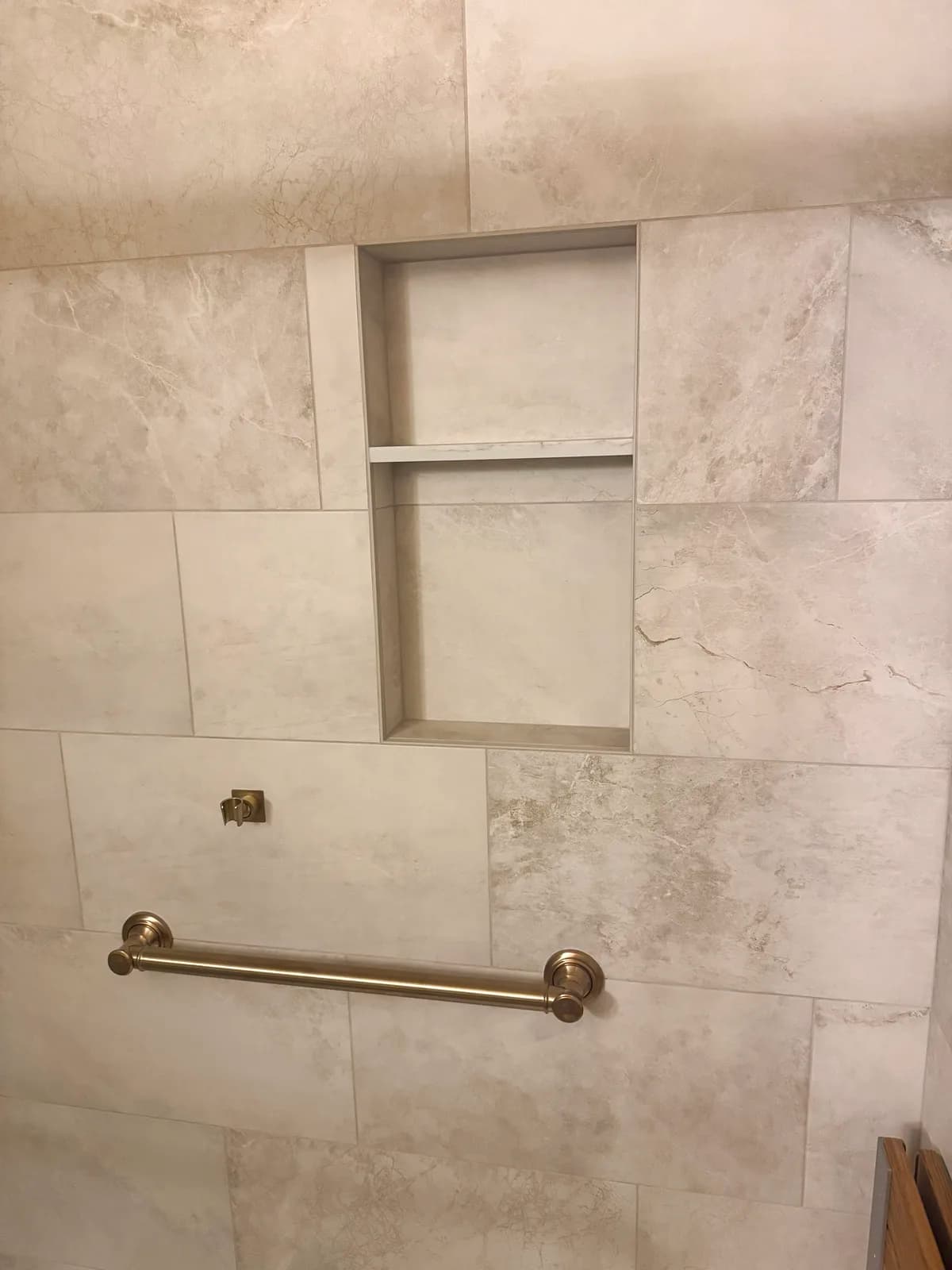 After: two recessed niches and a brushed gold grab bar in stone-look porcelain