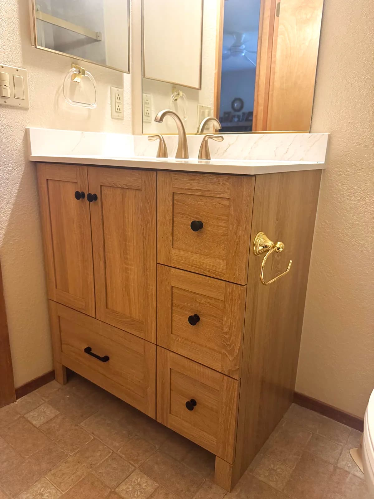 After: light oak vanity with new countertop and brushed gold faucet