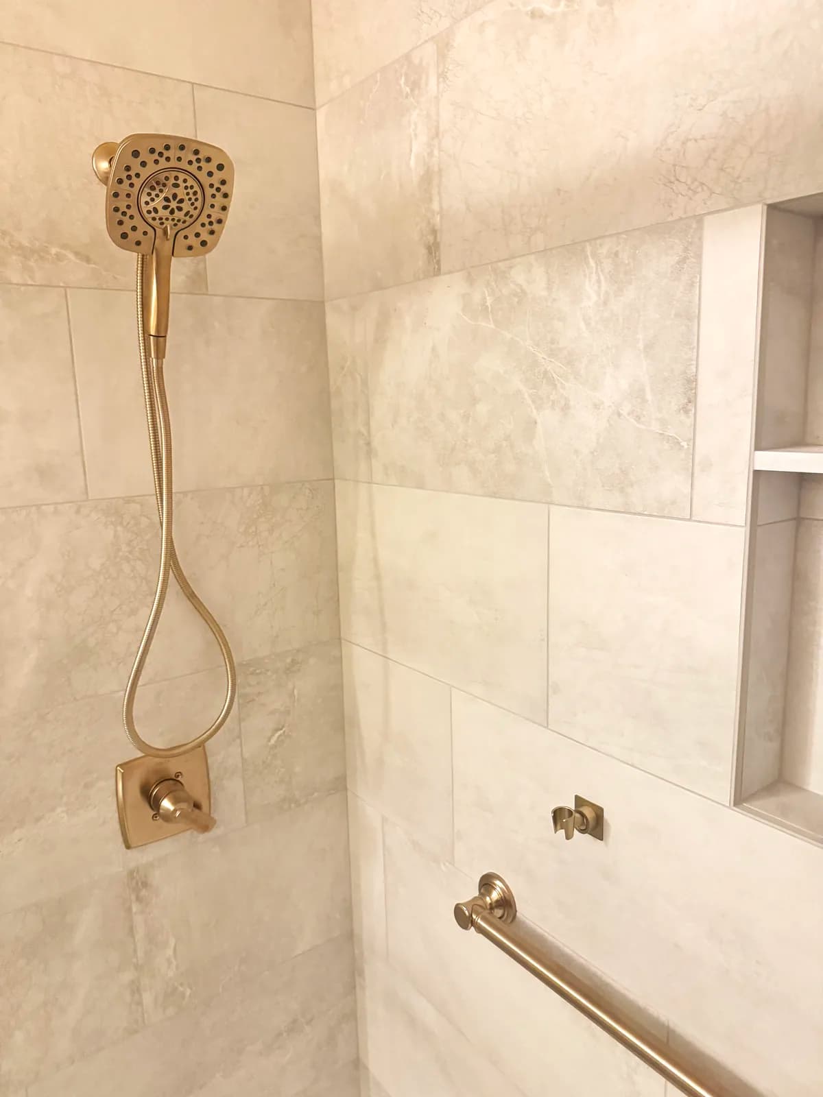 After: brushed gold handheld shower on the porcelain wall