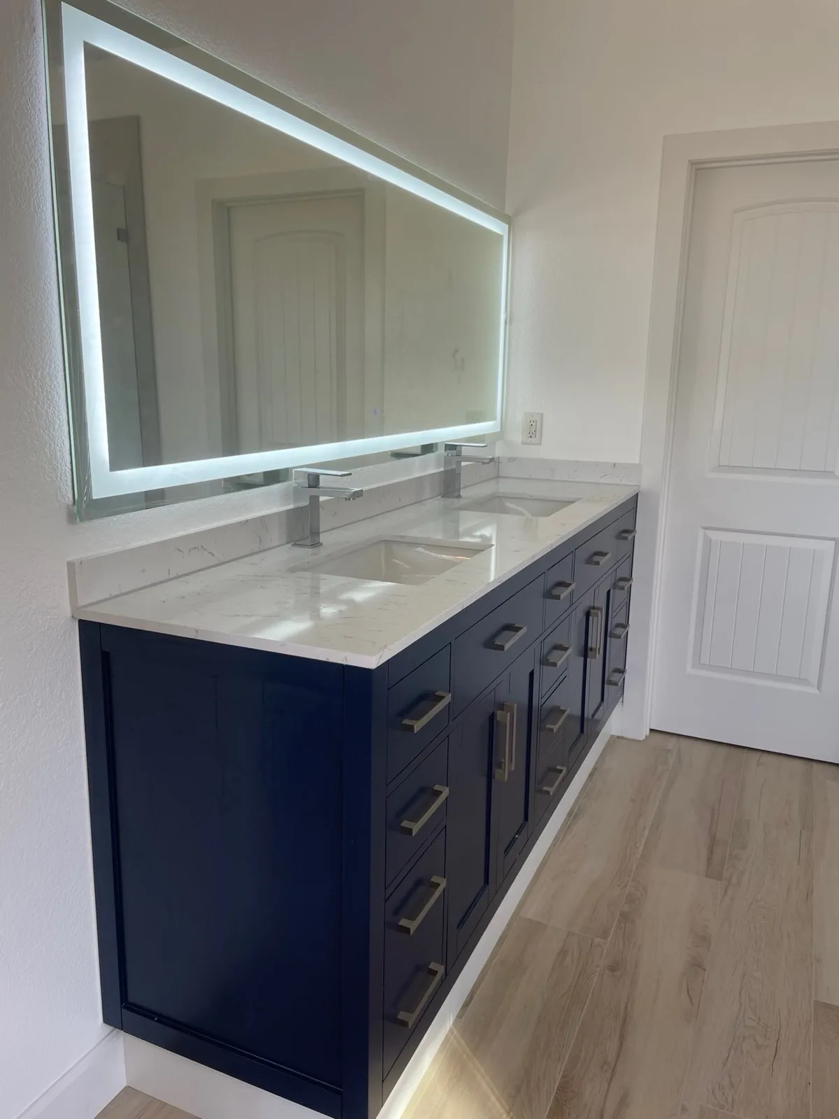 After: Pilot Hill master bathroom navy blue shaker double vanity with white quartz countertop and backlit LED mirror