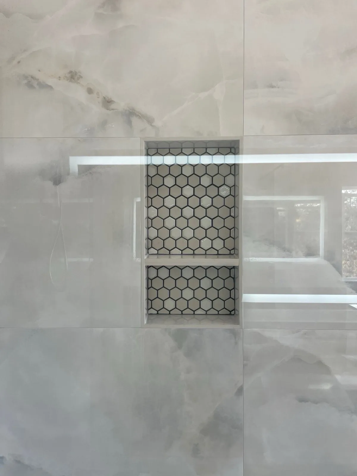 After: Pilot Hill shower niche detail — dual recessed niche with hex mosaic tile set into marble-look polished porcelain walls