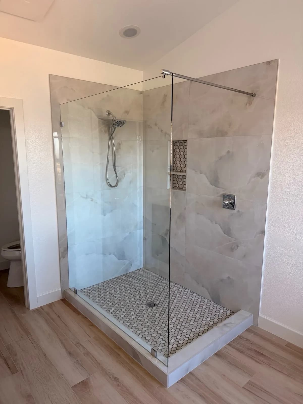 After: Pilot Hill master bathroom showing the full room width with open shower, wood-look flooring and new recessed lighting